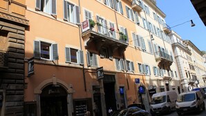 A multi-story building with balconies, storefronts, and parked vehicles. - 504 Corso Suites (Rome)