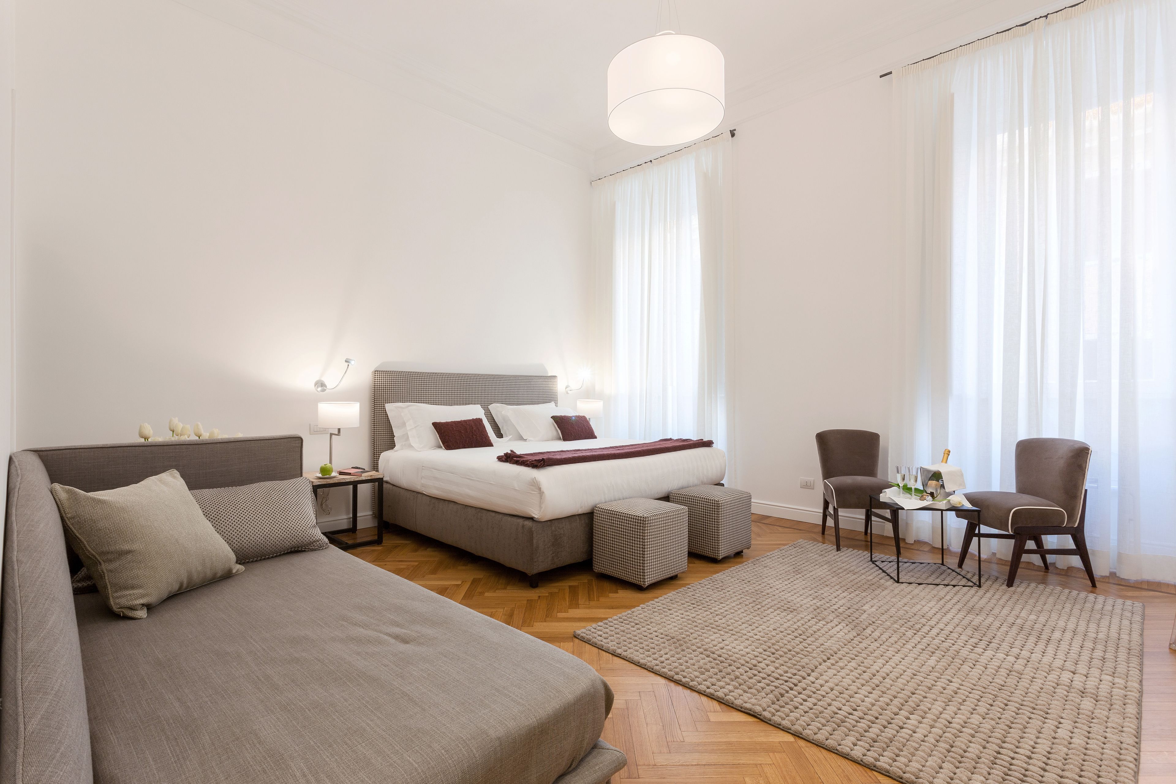 A modern bedroom with a large bed, a sofa, a small table, and two chairs.