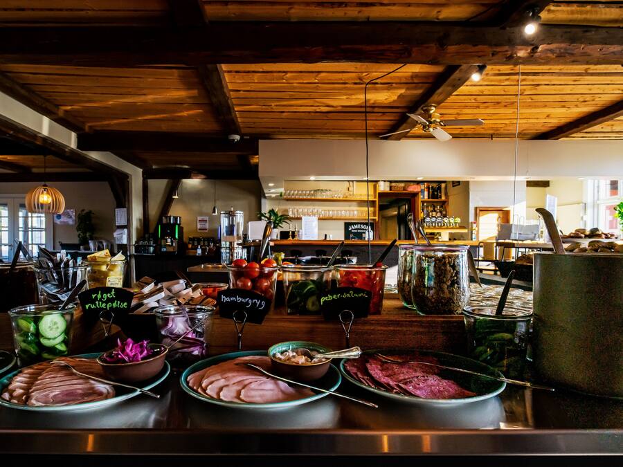 A buffet with various food items and a bar area in the background.