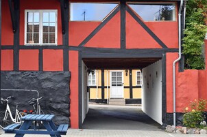 En bygning med sort-hvide bindingsværkselementer, rød facade og en lille indgang med en trädør.