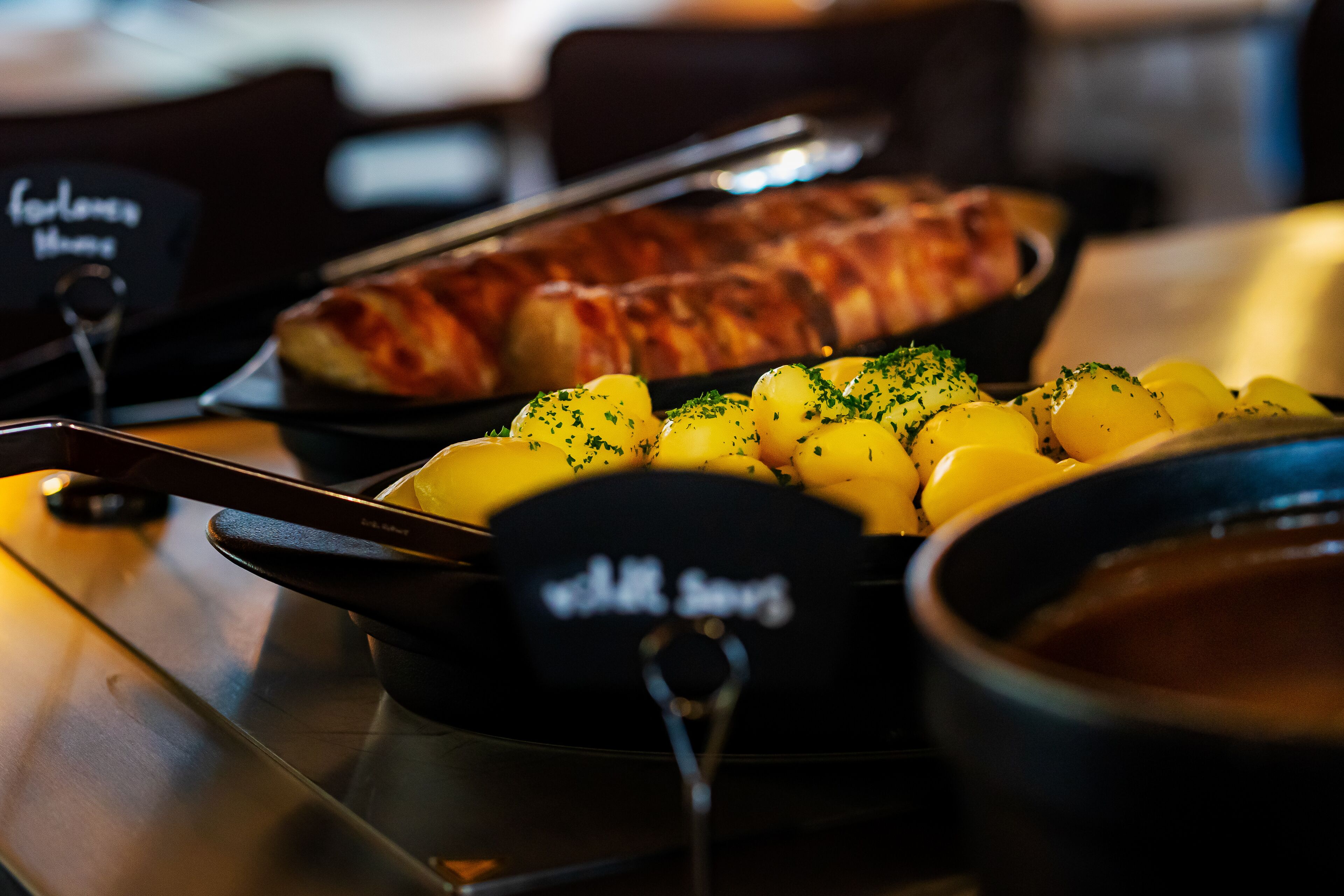 A buffet table with a variety of dishes including potatoes and a roasted item, likely a meat dish.