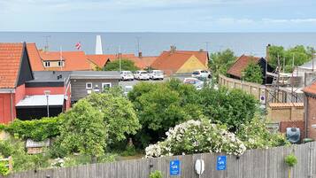 A coastal town with red-roofed buildings, a parking sign, and a view of the sea.