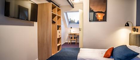 A bedroom with a bed, a desk, and a wardrobe.