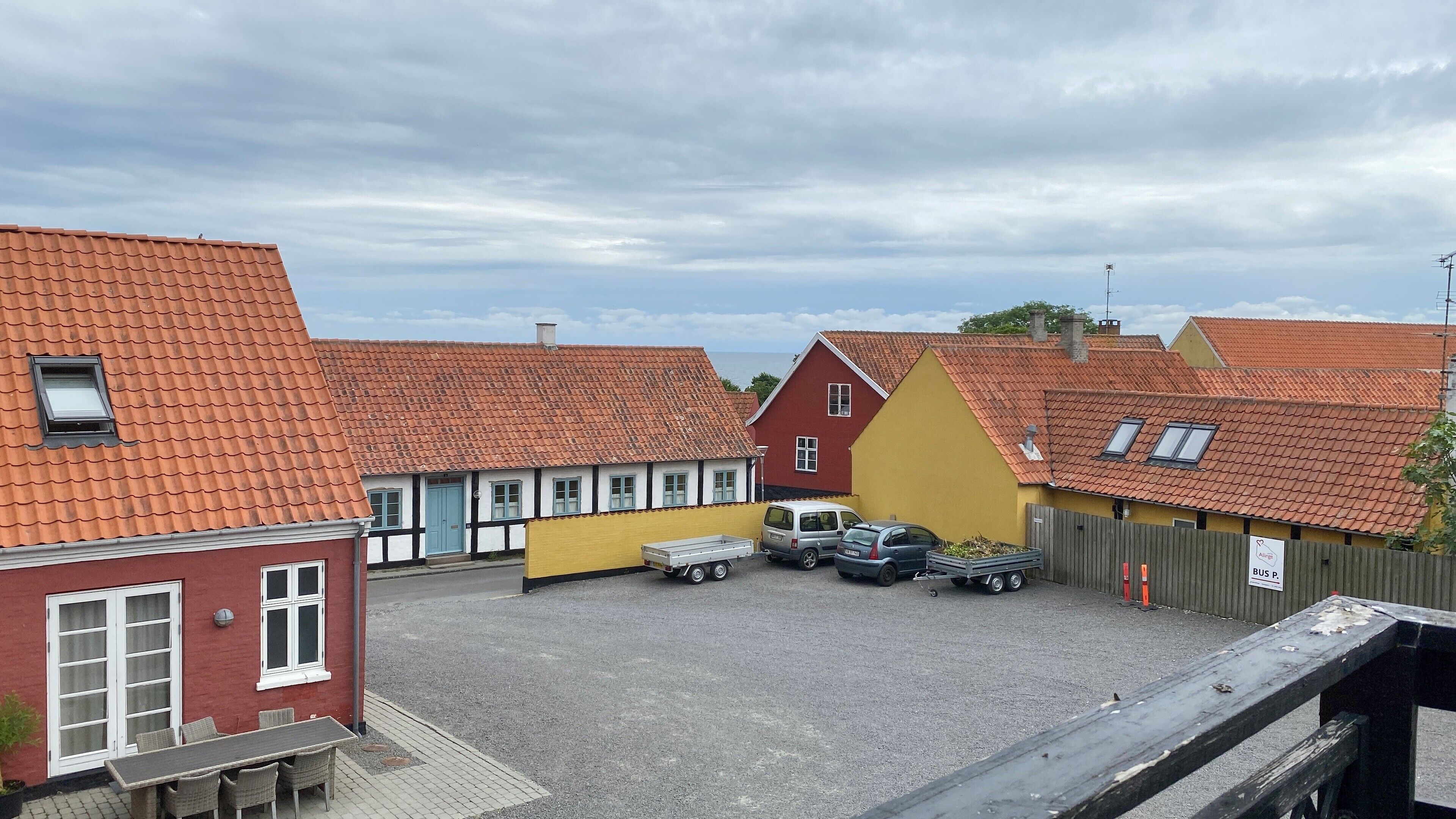 A courtyard with buildings, a truck, and parked cars.