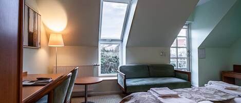 Een hotelkamer met een bed, een bureau, een stoel, een klein tafeltje en een bank.