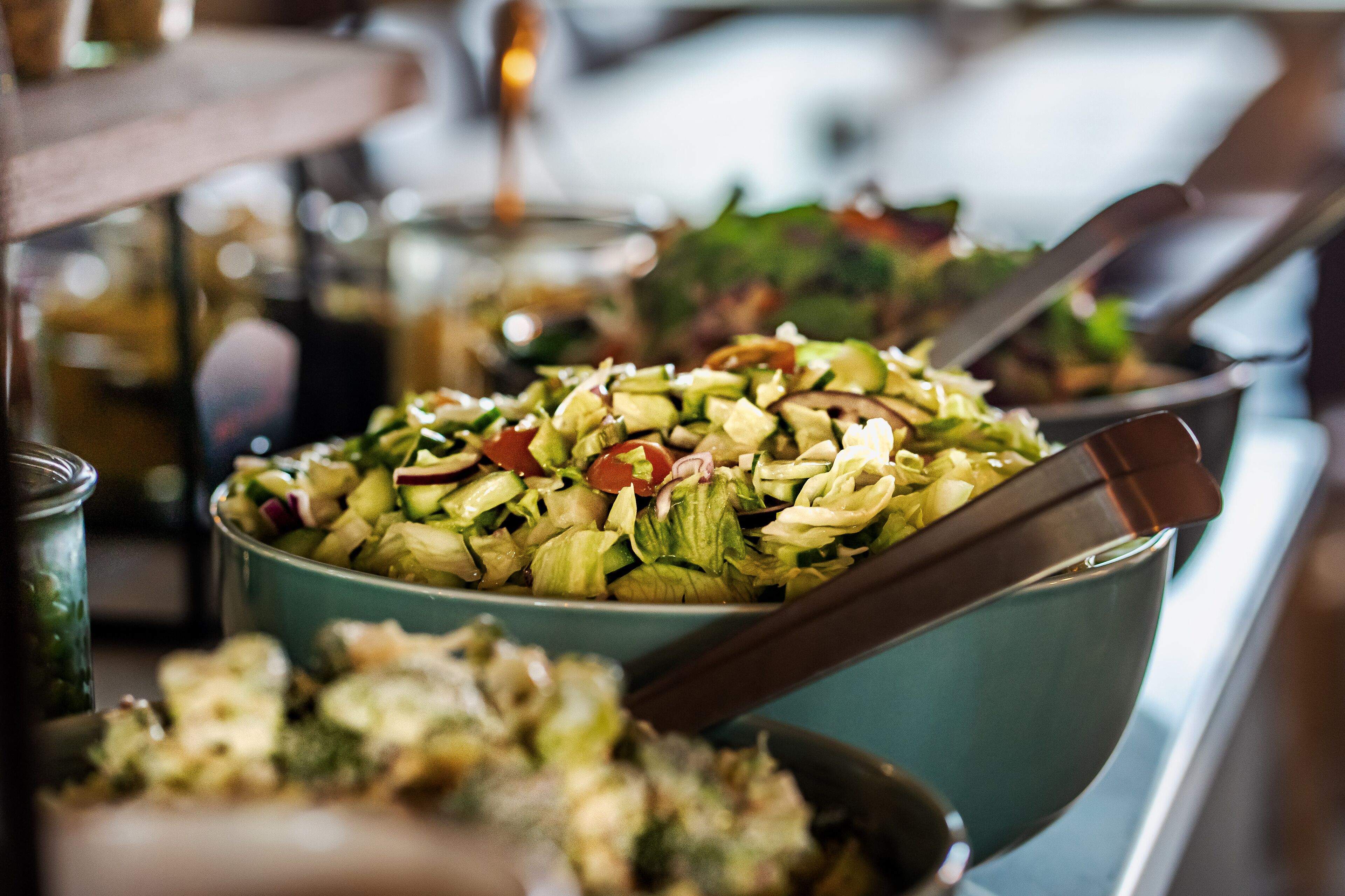 A buffet with various dishes, including a salad with vegetables and nuts, and a casserole dish.