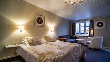 A hotel room with two beds, a desk, a chair, and a view of the outdoors.
