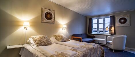 Habitación de hotel con dos camas, un escritorio, una silla y vistas al exterior.