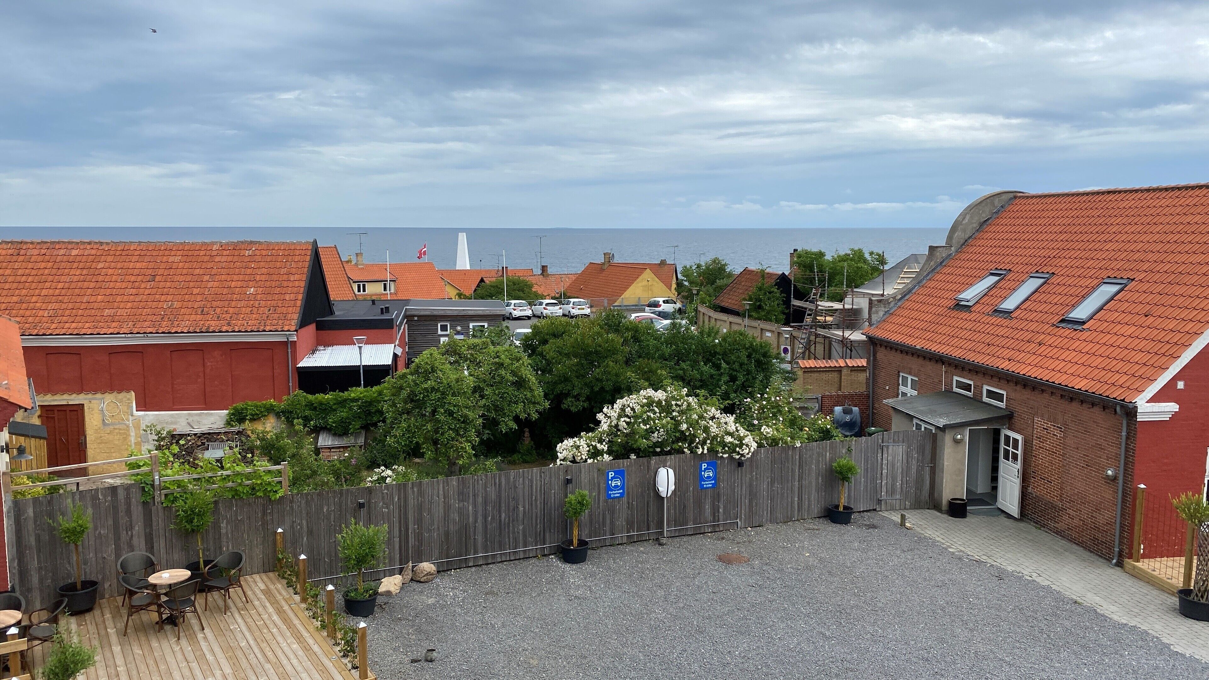 Ein Innenhof mit Holzzaun, Kübelpflanzen und Kiesfläche.