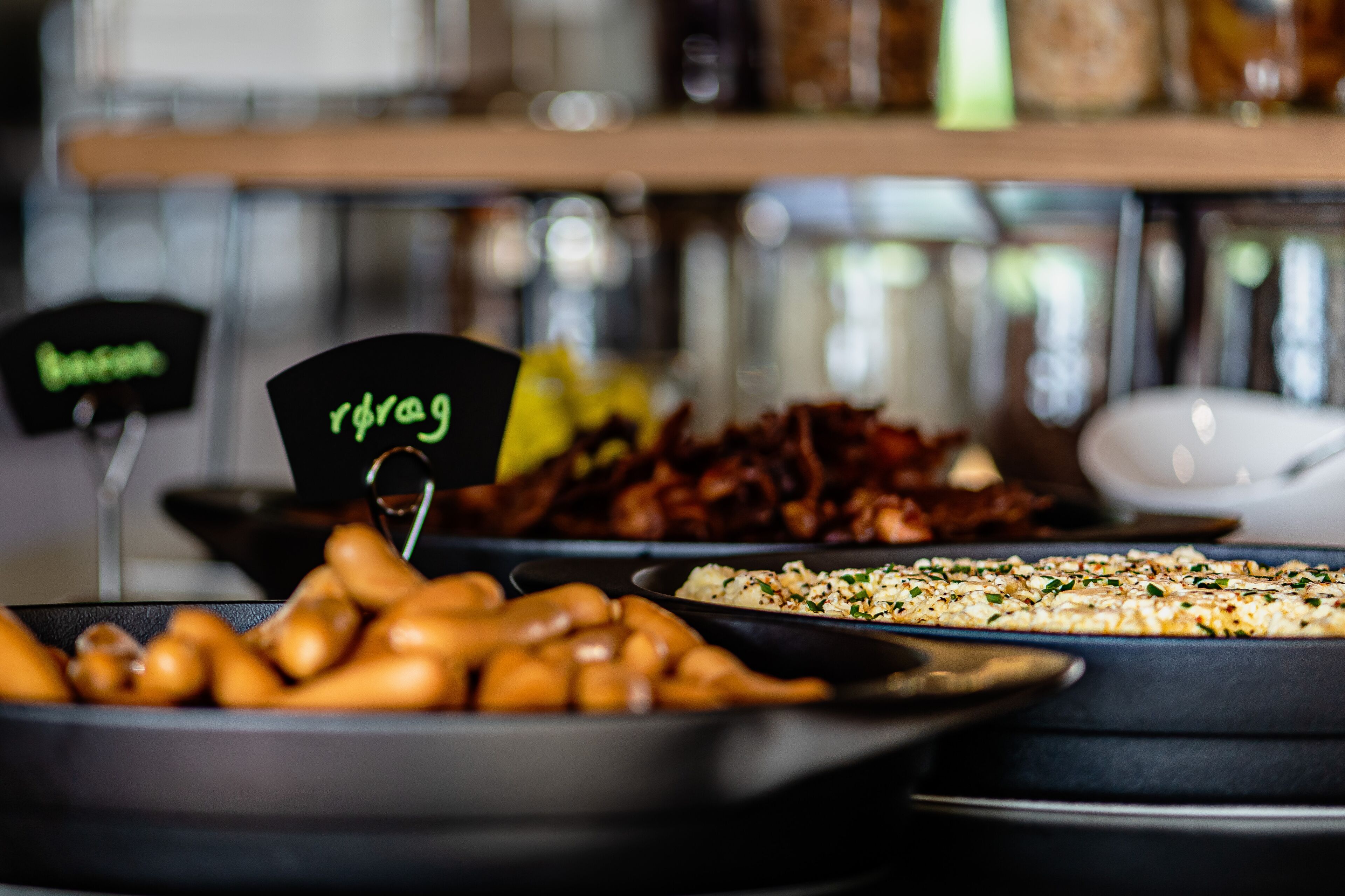 A buffet with various dishes including roasted potatoes, bacon, and a casserole.