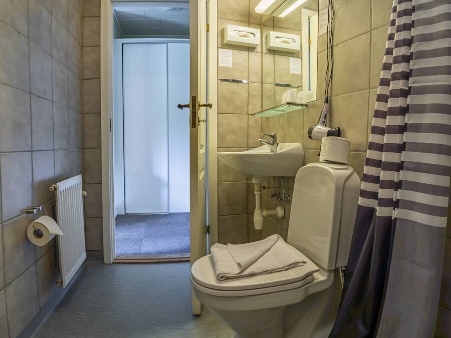 Un baño con inodoro, lavamanos y cortina de ducha.