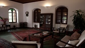 A traditional room with a wooden cabinet, a large arched window, and a red carpet. - Hiliki House (Zanzibar Town)