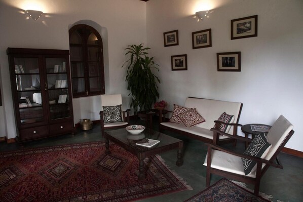 Un salón tradicional con sofá, sillones, una mesita de centro, un aparador y una planta grande.