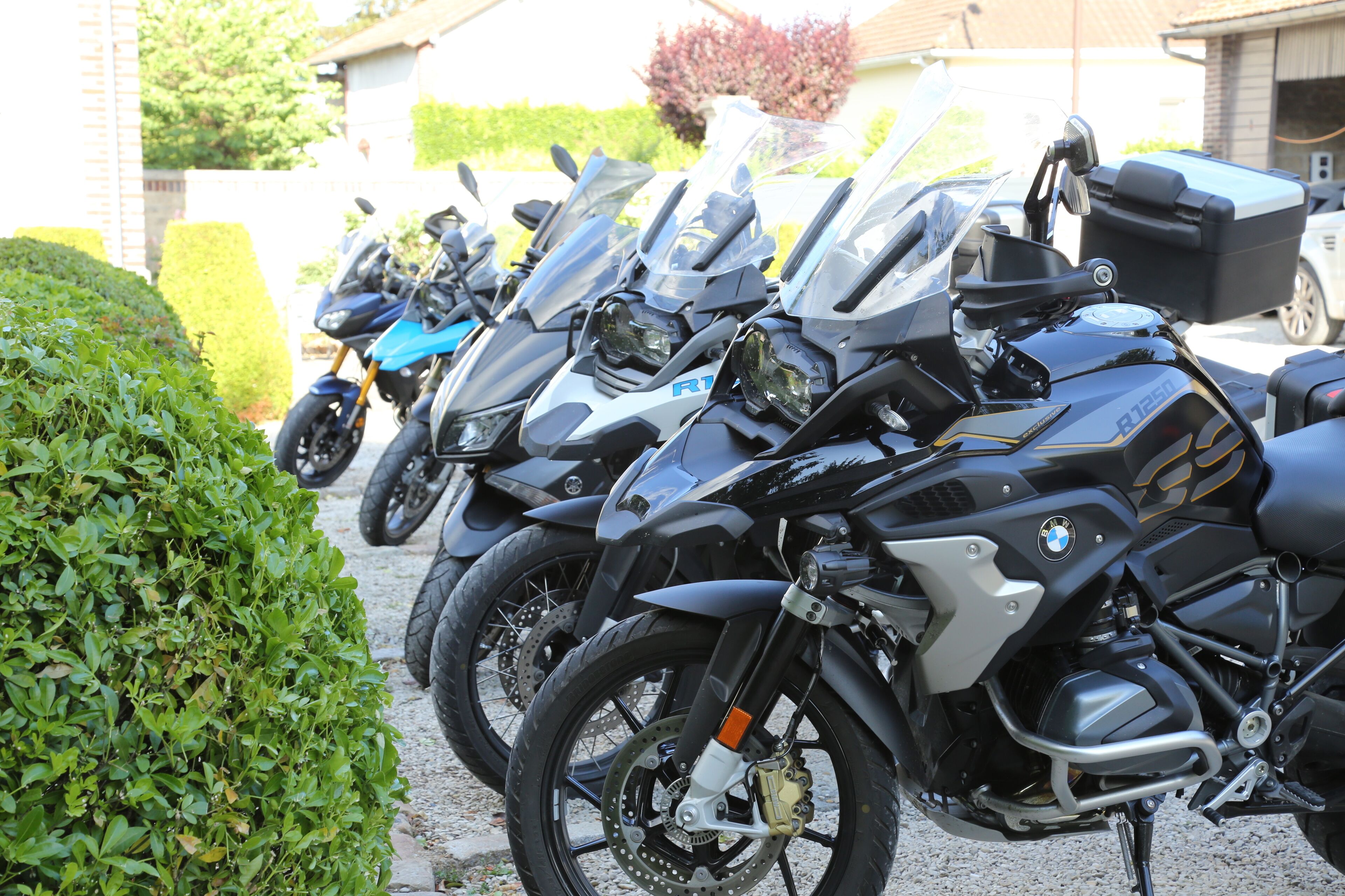 A row of parked motorcycles, including a BMW R1250GS, in a parking lot.