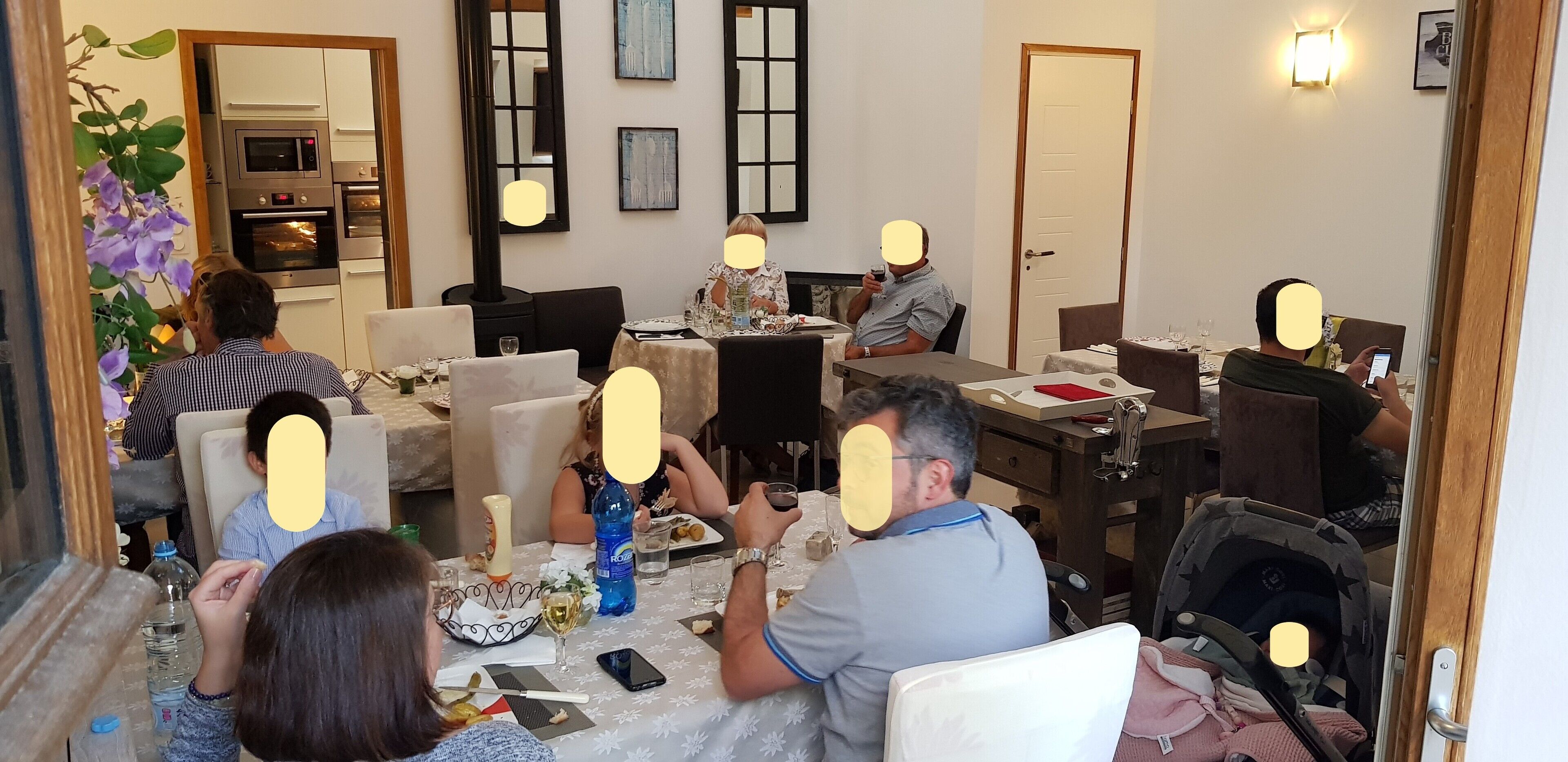 A dining area with a kitchen in the background, a baby stroller, and a dining table with food and drinks.