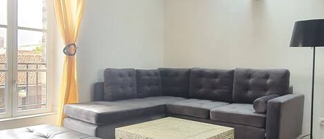 Una sala de estar moderna con un sofá seccional, una mesa de centro y una araña.