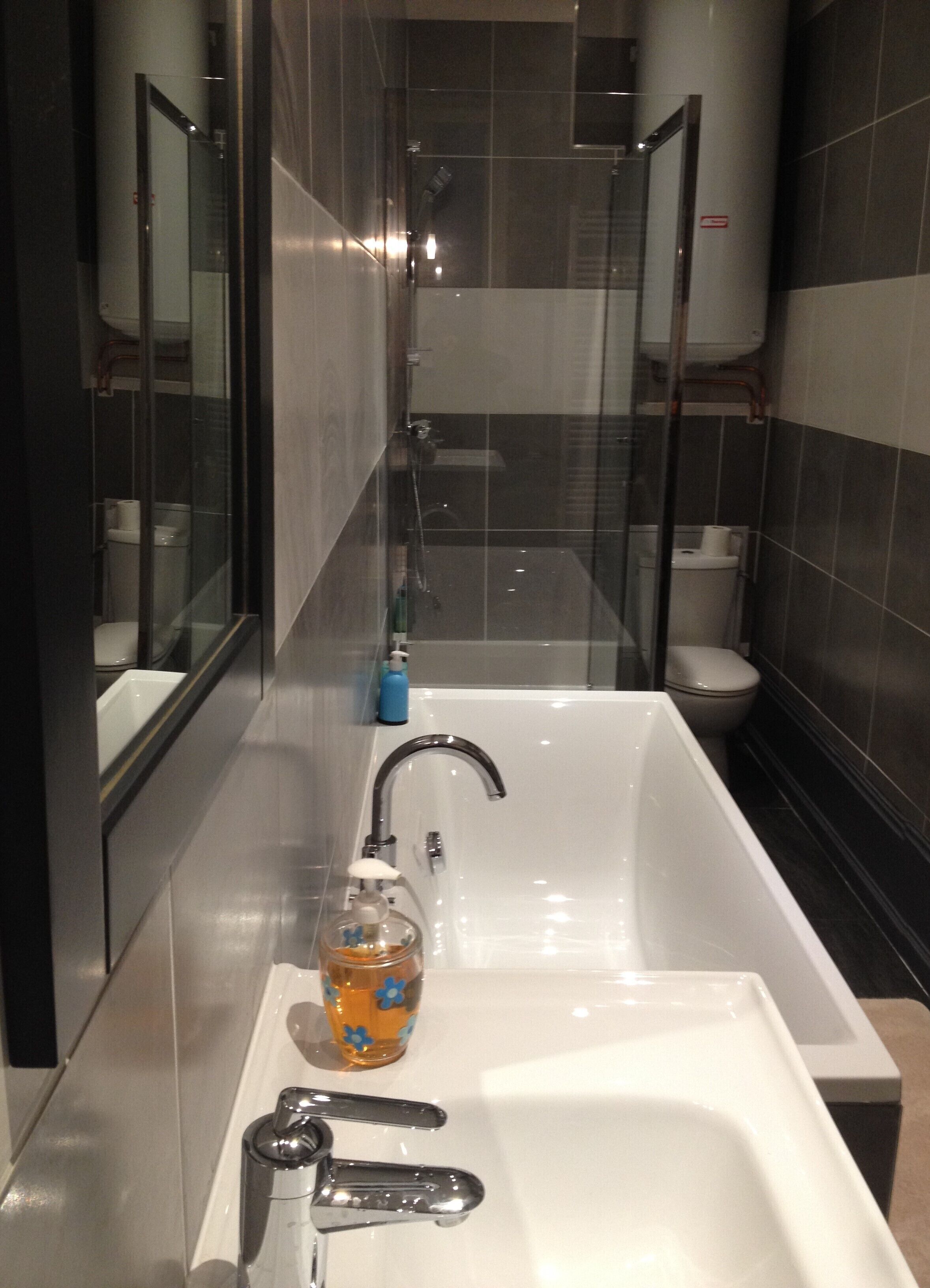 A modern bathroom with a bathtub, a toilet, and a shower area.