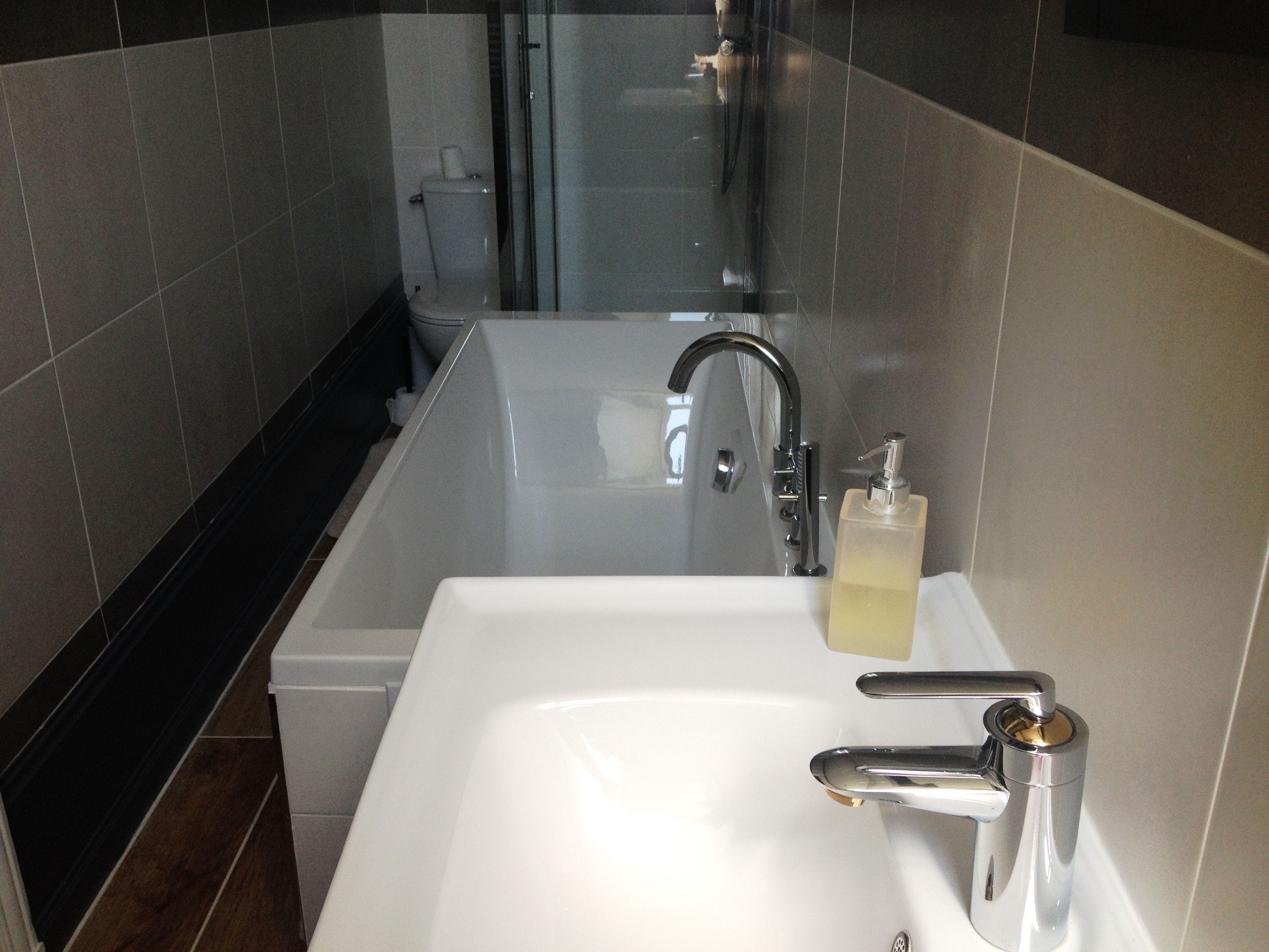 Un baño moderno con un lavamanos blanco, grifo cromado y cabina de ducha de vidrio.