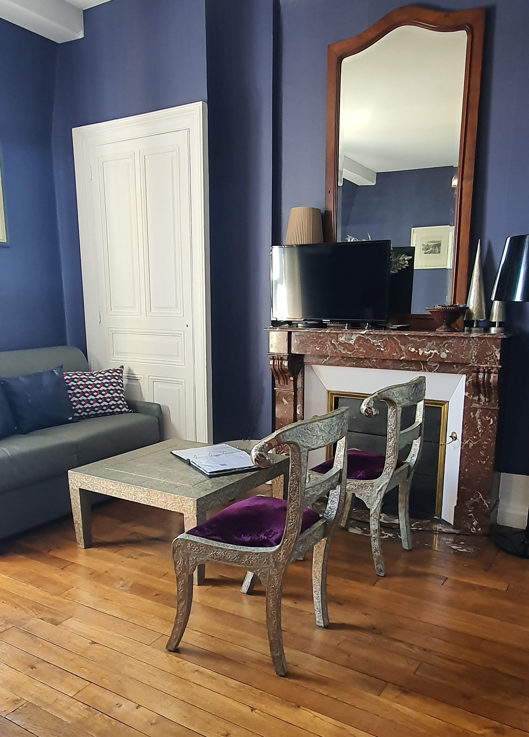 A living room with a sofa, a coffee table, two chairs, a television, and a fireplace.