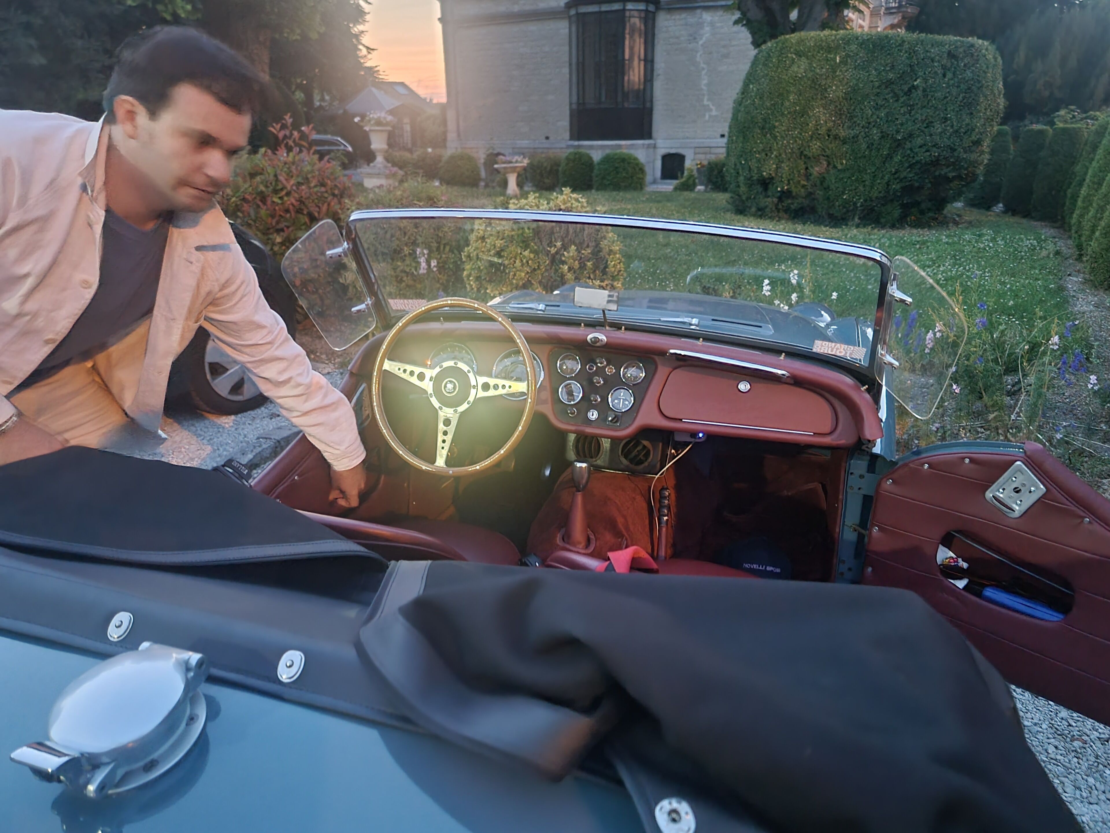 A vintage convertible car interior with a steering wheel, dashboard, and manual gear shift.