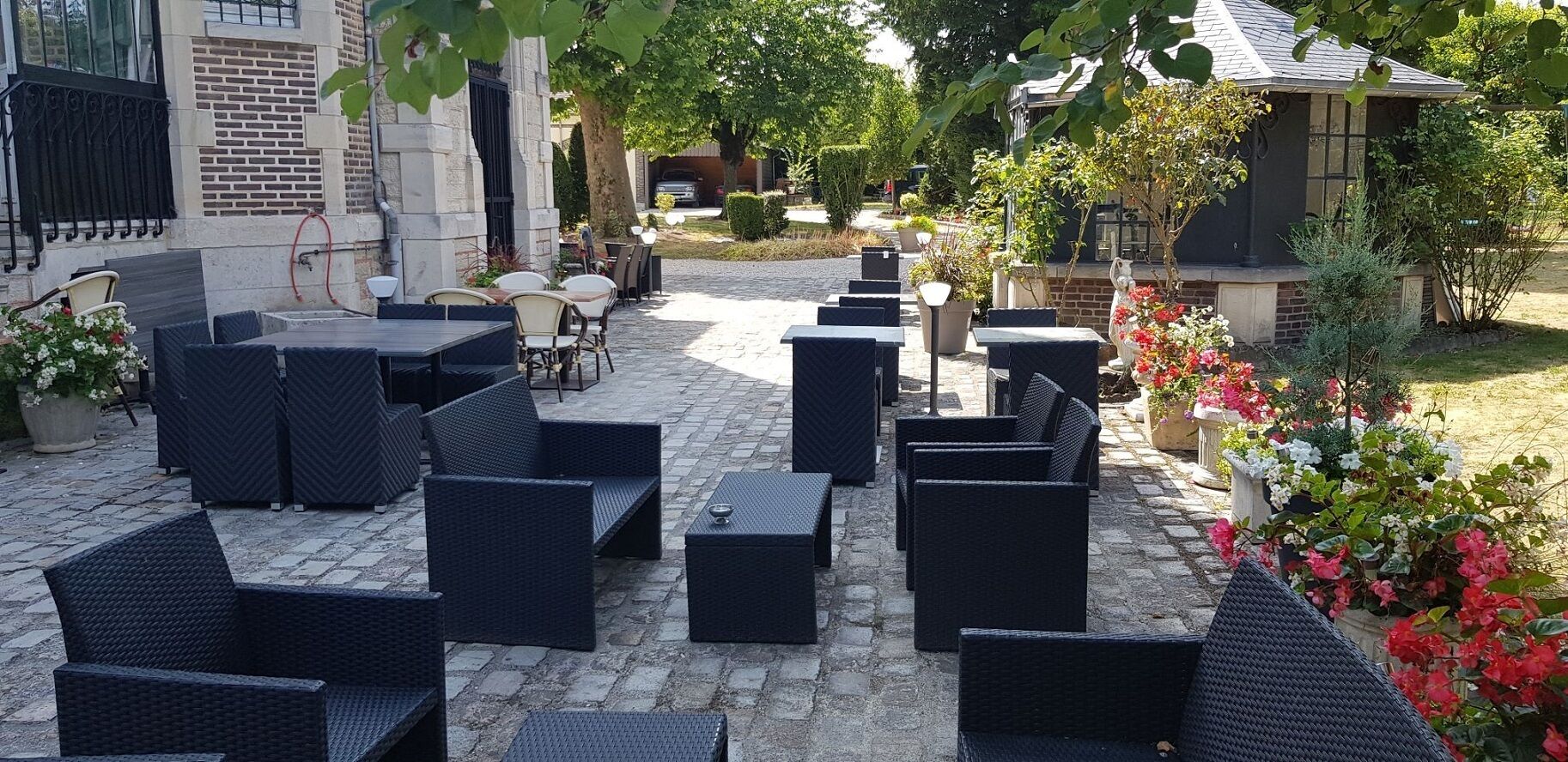 An outdoor patio with wicker furniture and potted plants.