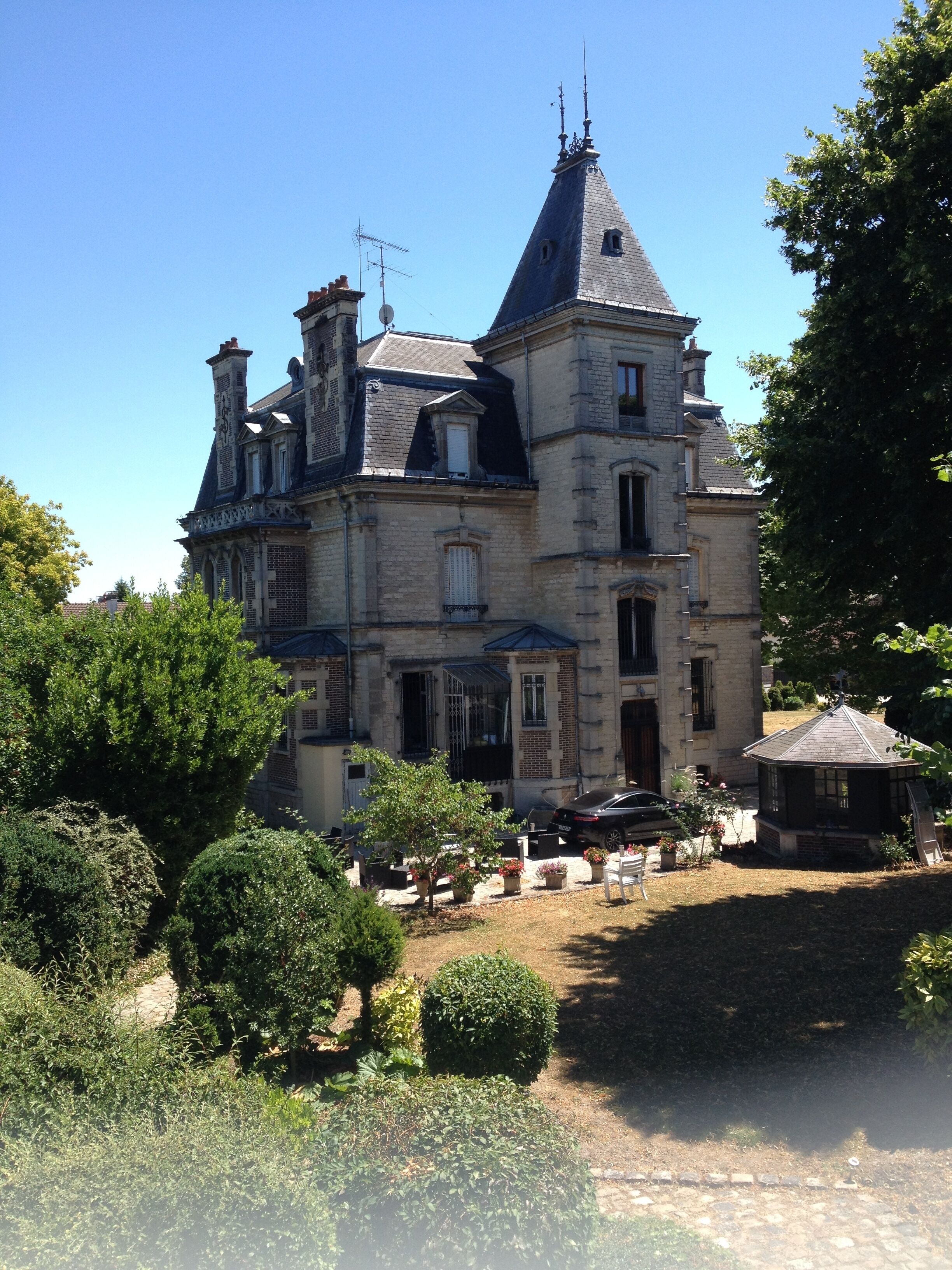 Un grand bâtiment historique en pierre, doté de nombreuses cheminées et d’une tour imposante.