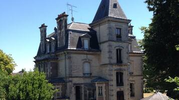 Un grand bâtiment historique en pierre, doté de nombreuses cheminées et d’une tour imposante.