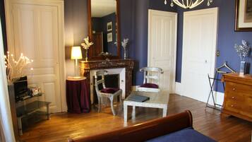 A room with a bed, a fireplace, a mirror, a chandelier, and a dresser.