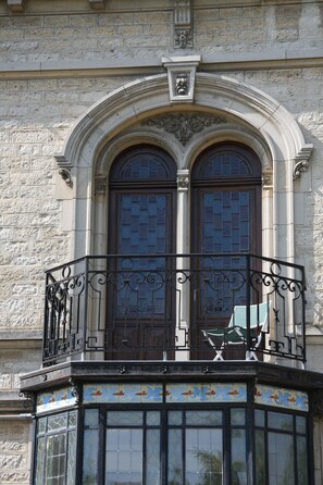 A building with a balcony featuring ornate metal railings and a decorative tile base. - Villa Primerose (Arcis-sur-Aube)