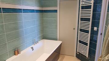 Une salle de bain moderne dotée d’une grande baignoire, d’un espace douche séparé et d’une douche à parois de verre.