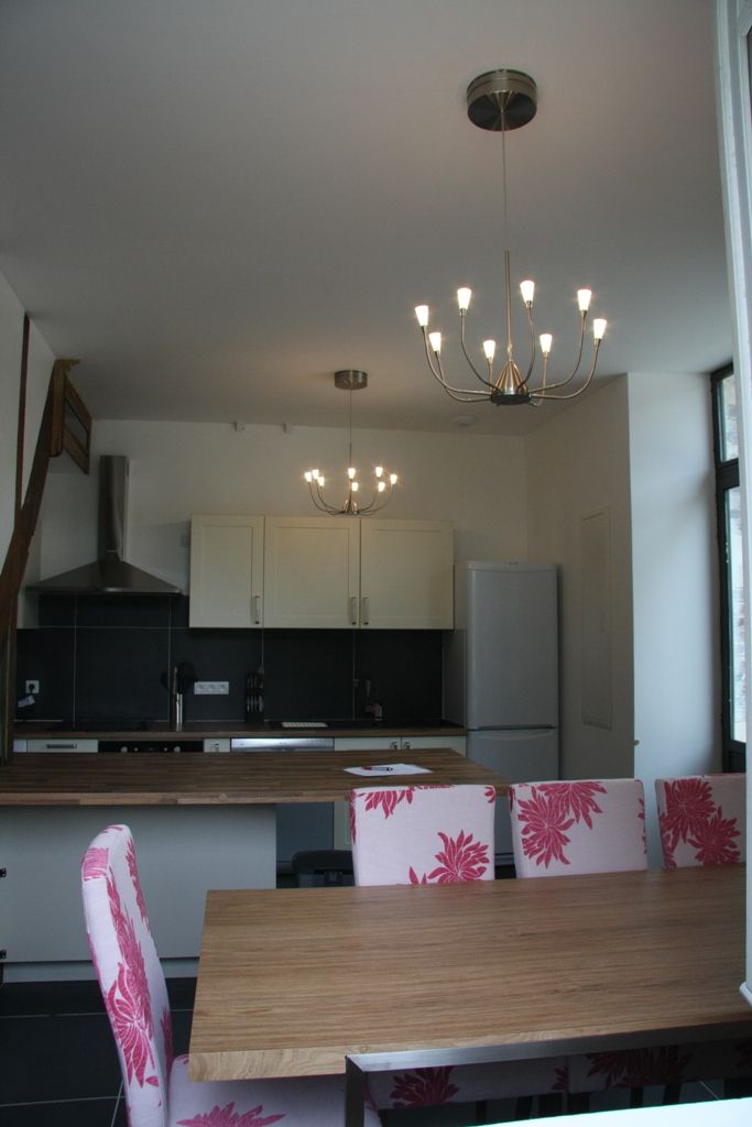 A modern kitchen with a central island, a dining table with floral chairs, and a chandelier.
