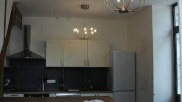 A modern kitchen with a central island, a dining table with floral chairs, and a chandelier.