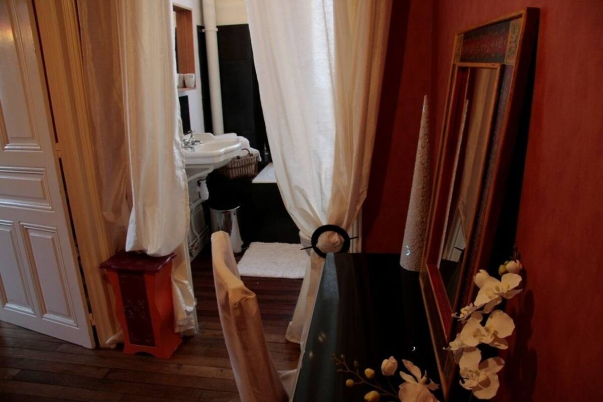Casa de banho com lavatório, espelho e um banquinho pequeno.