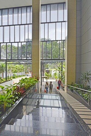 A spacious indoor area with large windows, a central staircase, and a plant-lined walkway. - Travello Bandung (Bandung)
