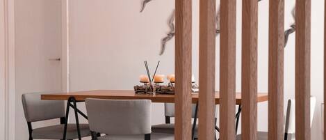 A dining area with a wooden table, grey upholstered chairs, and a decorative wall with bird silhouettes.
