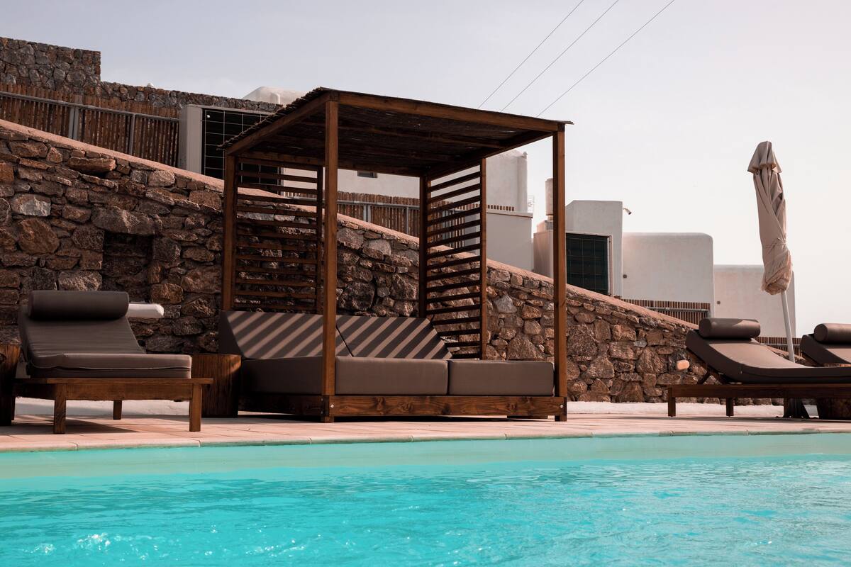 A poolside area with lounge chairs and a wooden pergola.