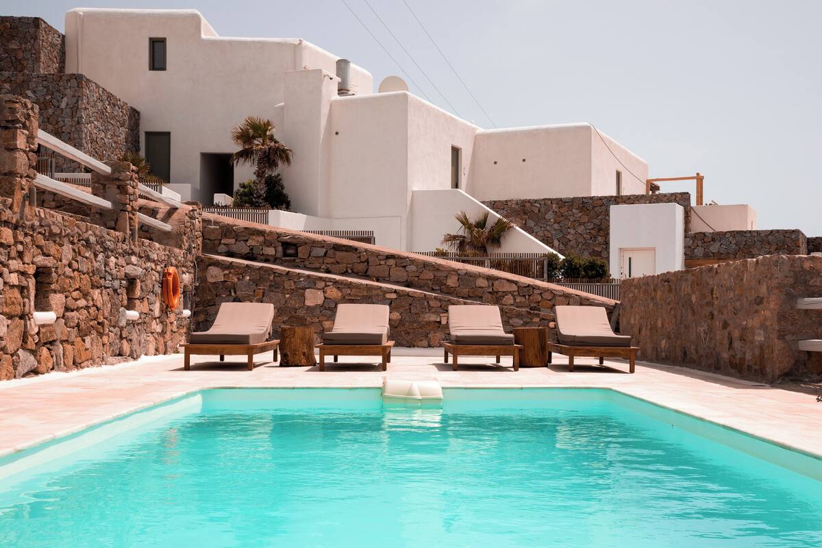 A pool area with lounge chairs and a stone wall.