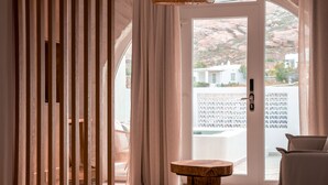 A room with a wooden slat partition, a round wooden table, and a view through a glass door to the outside. - Senses Villas (Mykonos)
