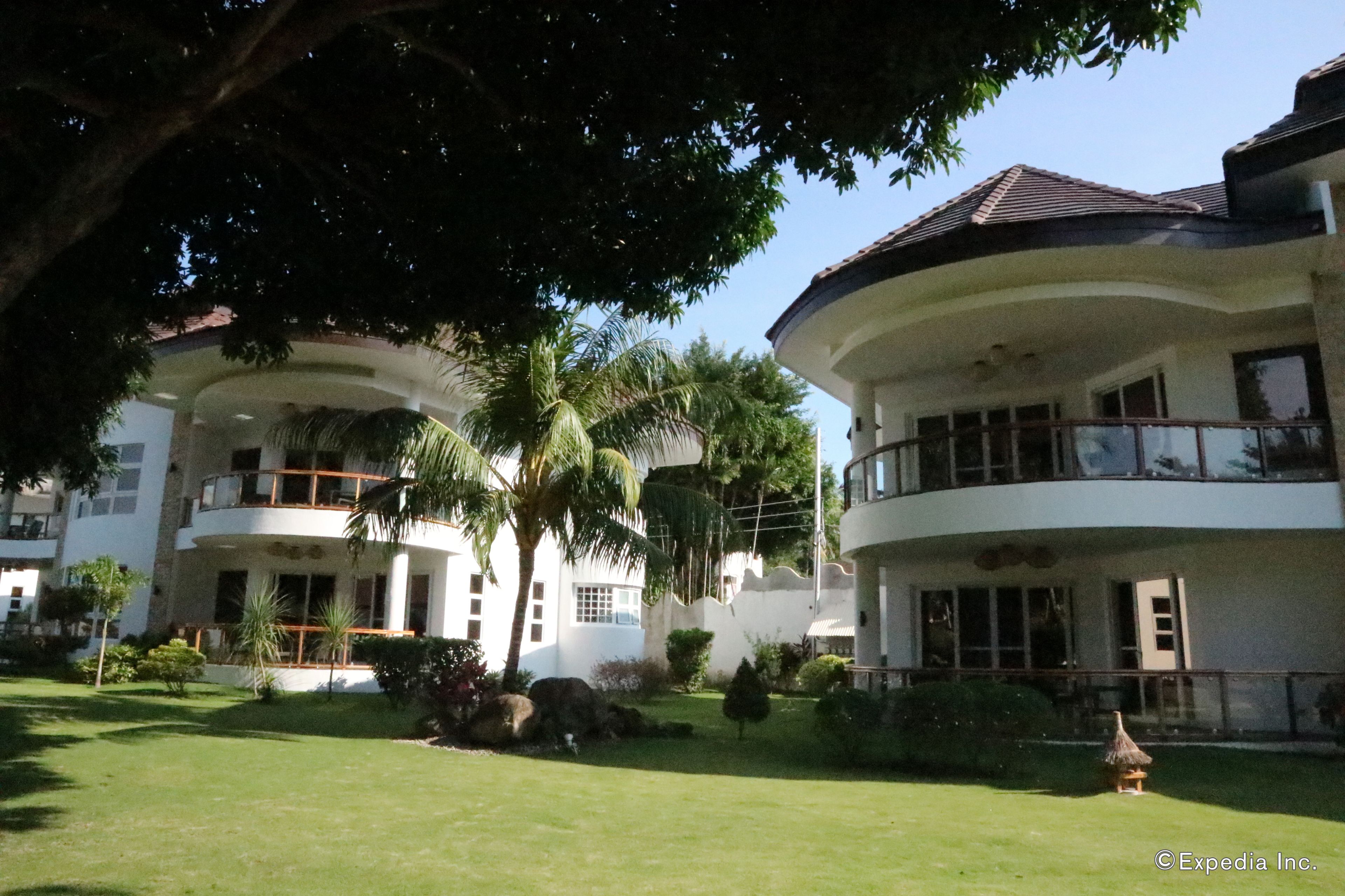 A multi-story building with balconies, surrounded by well-maintained lawns and palm trees.