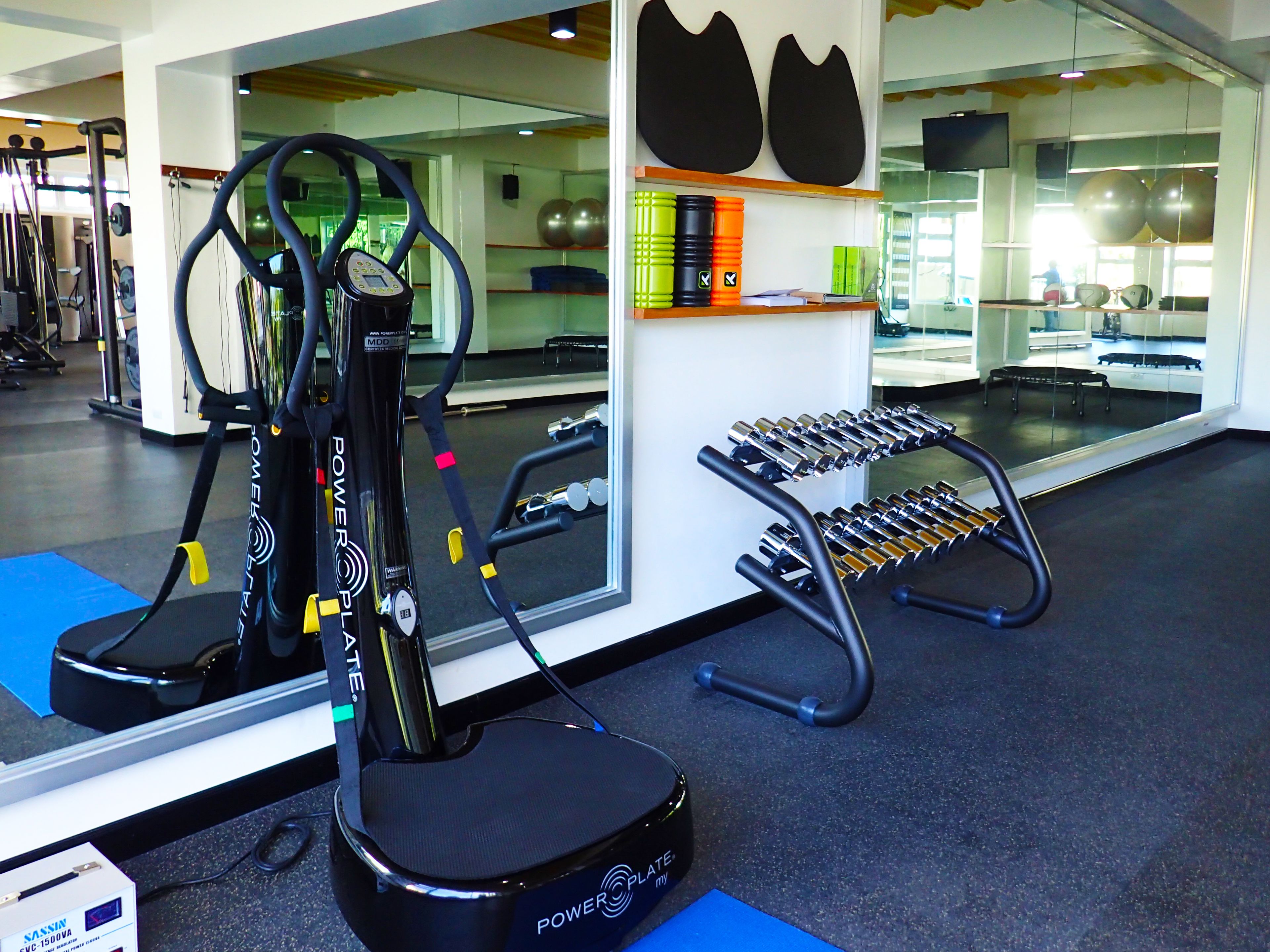 Un gimnasio con equipo de ejercicio, incluyendo una bicicleta estática, mancuernas y un espejo.