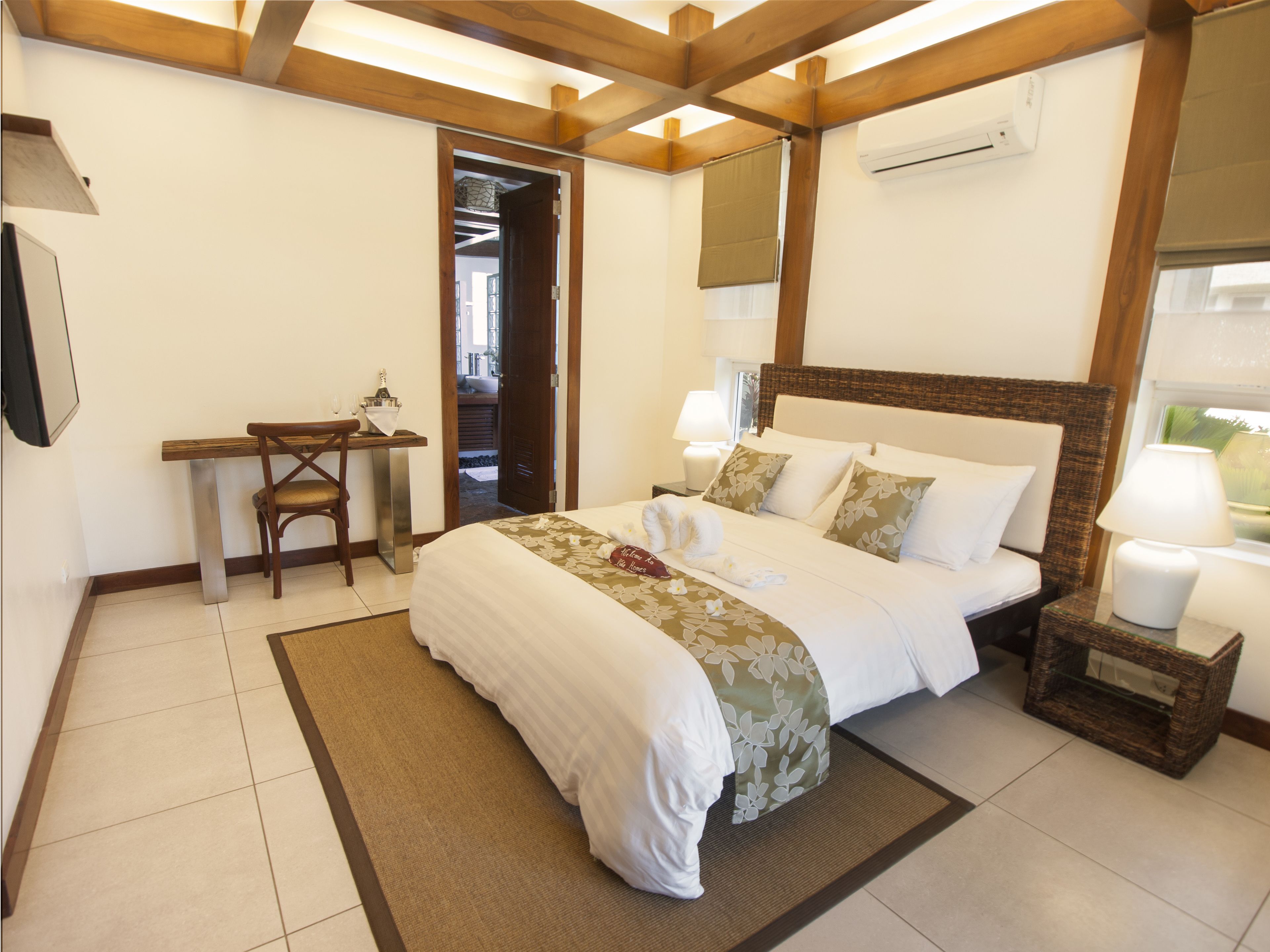 Quarto de hotel com cama, mesas de cabeceira, escrivaninha e uma cadeira.