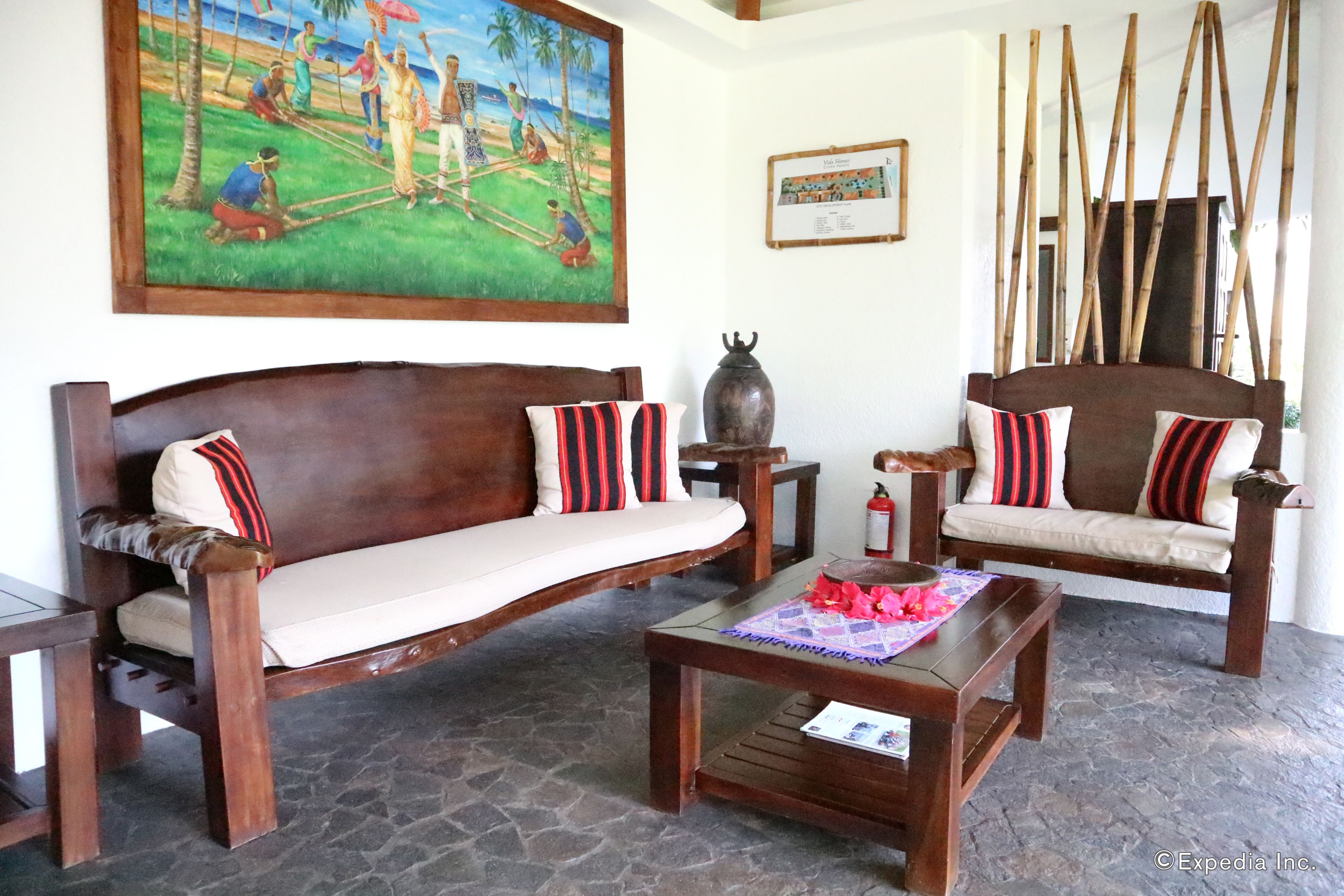 A traditional wooden sofa with striped cushions, a matching wooden table, and a stone floor.