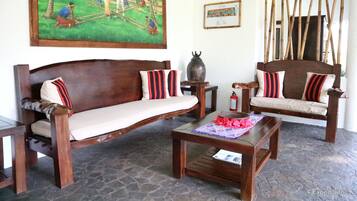 A traditional wooden sofa with striped cushions, a matching wooden table, and a stone floor.