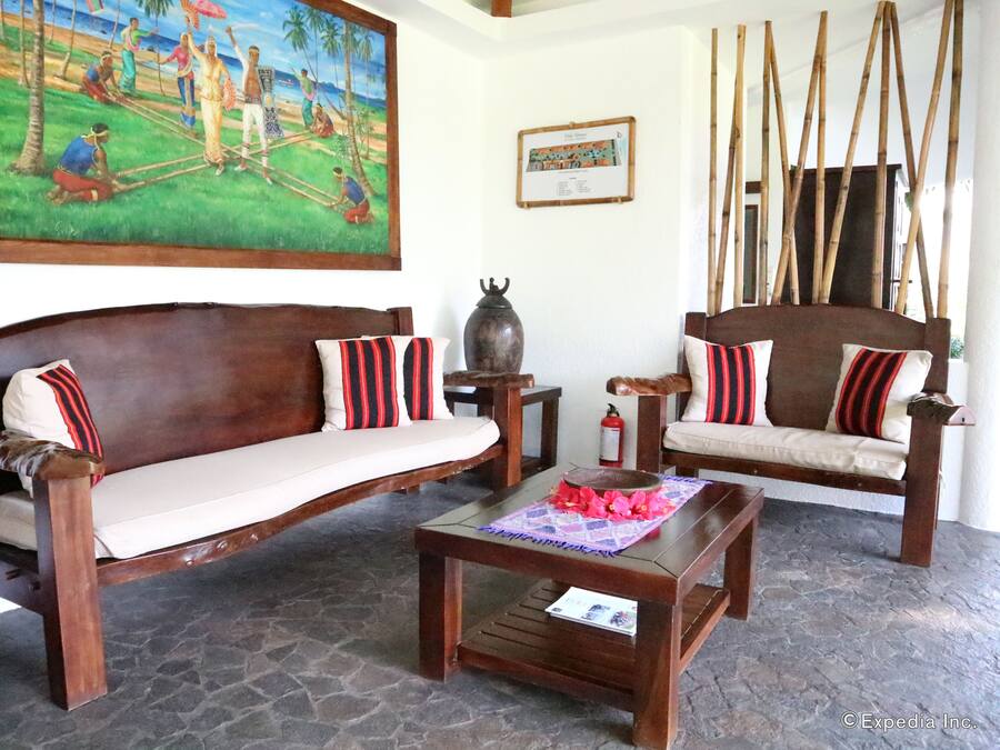 A traditional wooden sofa with striped cushions, a matching wooden table, and a stone floor.