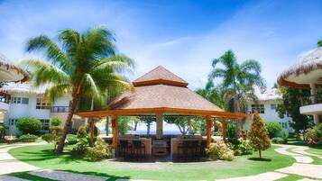 A resort with a central gazebo, palm trees, and a clear view of the ocean.