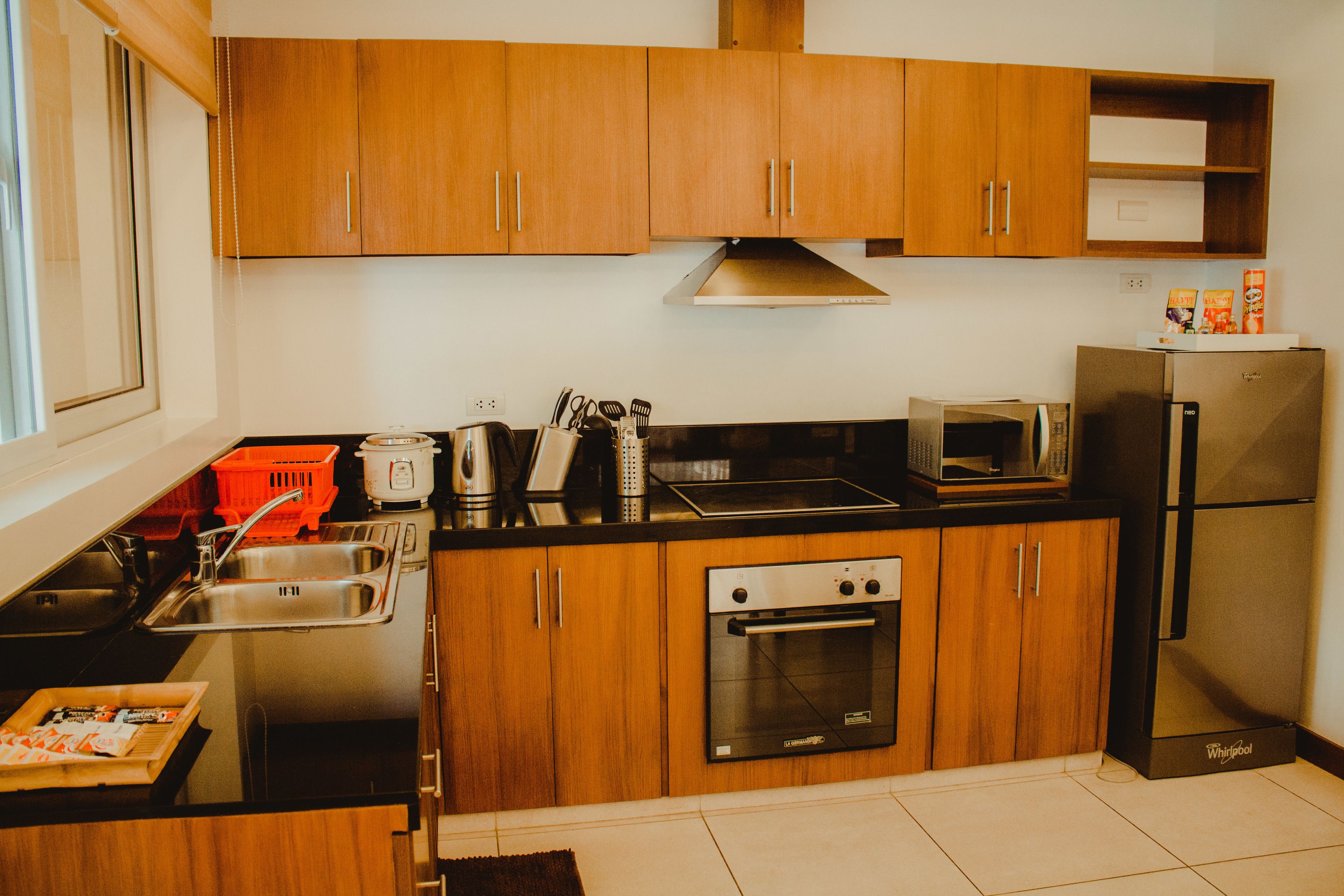 A modern kitchen with wooden cabinets, a stainless steel sink, a microwave, a refrigerator, and an oven.