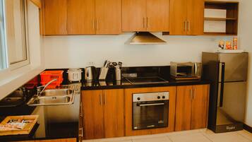 A modern kitchen with wooden cabinets, a stainless steel sink, a microwave, a refrigerator, and an oven.