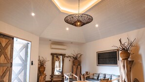 Un salon spacieux doté d’un plancher en bois, d’un grand canapé, d’une table basse et d’un luminaire suspendu.