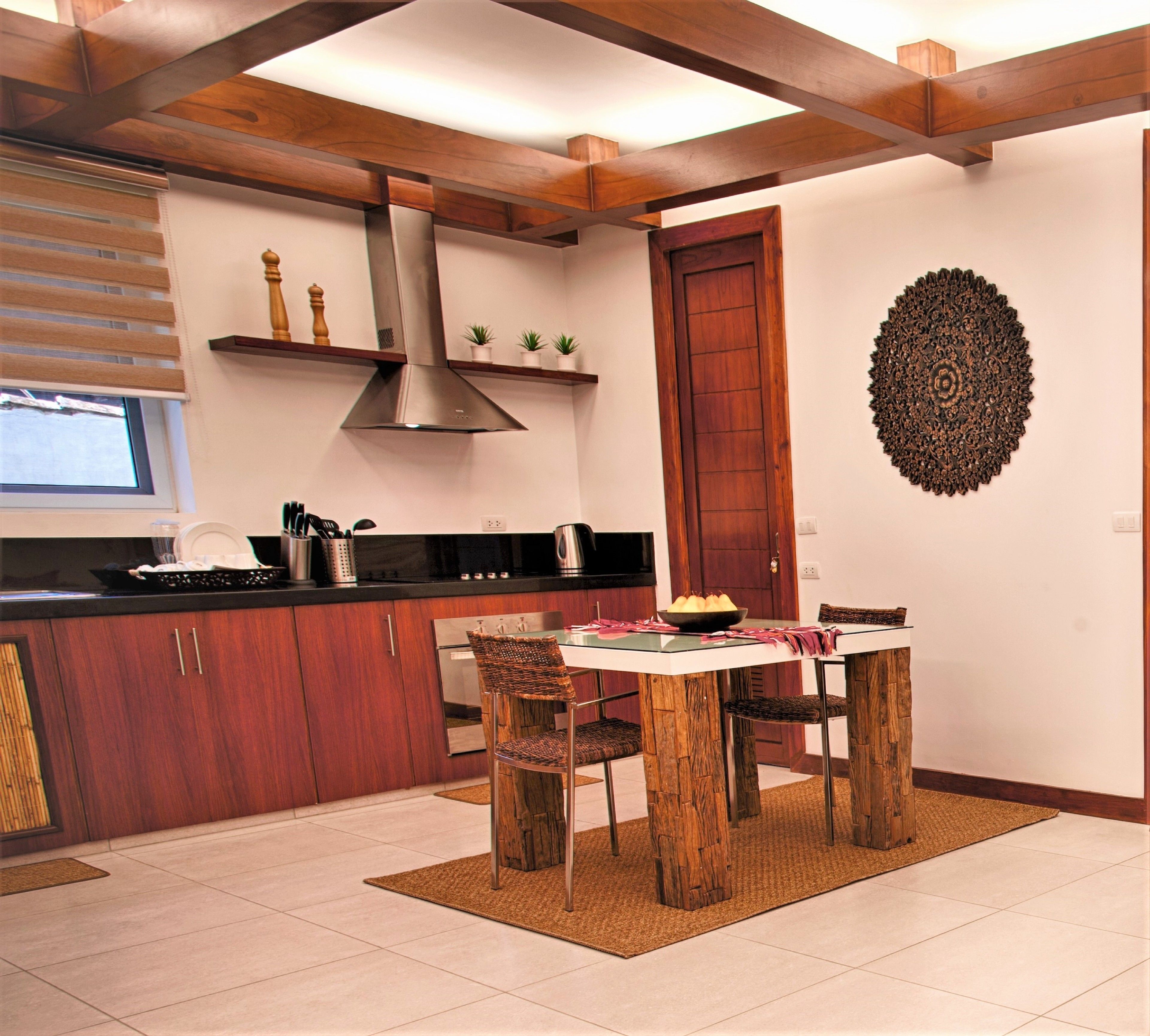 A kitchen with wooden cabinets, a stainless steel range hood, and a dining area with a wooden table and chairs.