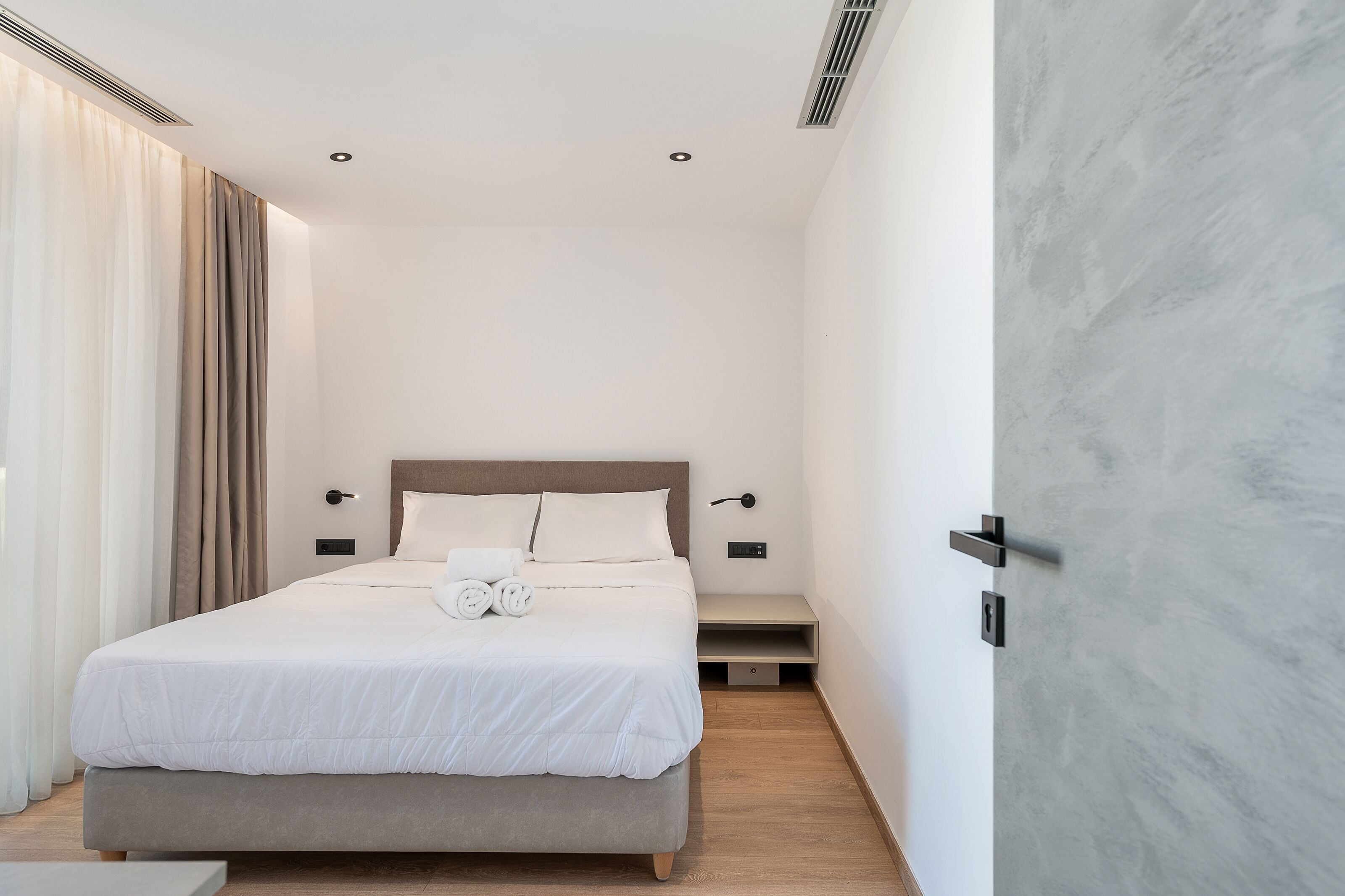 Ett modernt hotellrum med en stor säng, sängbord och en vägg som har en dekorativ marmorbeklädnad.